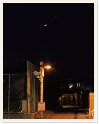 空に月と木星が見えており、道路が街灯で照らされている様子