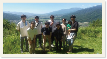 麓を見下ろす山頂に並んだ地域の方とメンバー