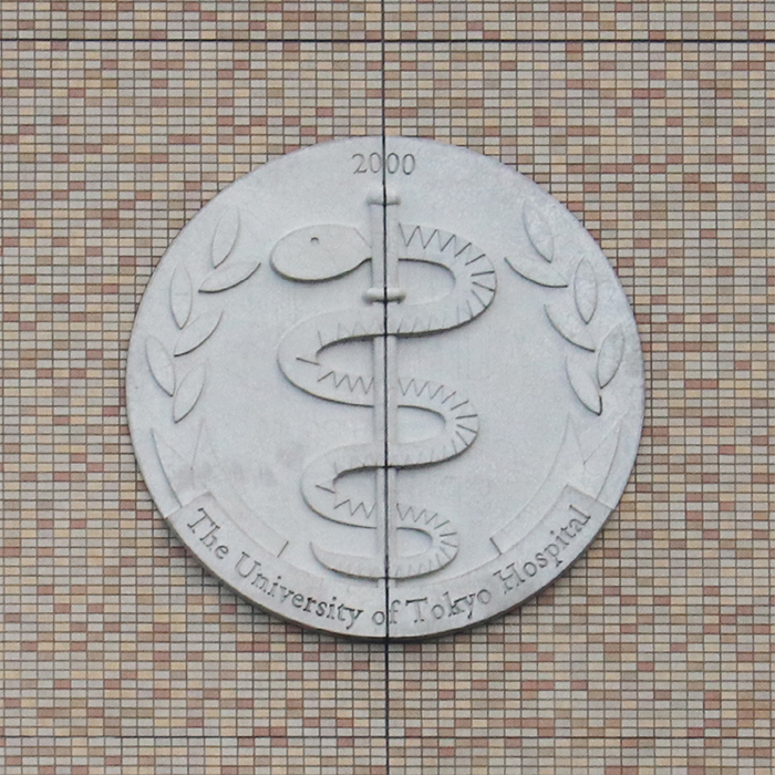 ヘビと杖がデザインされている「The University of Tokyo Hospital」と書かれた円形のレリーフ