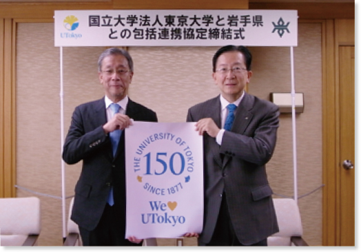 藤井総長と達増知事のツーショット写真。創立150周年キャンペーンの紙を掲げている
