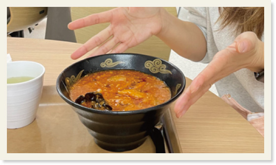 赤門ラーメンの写真。黒い器にオレンジ色のあんかけラーメンが入っている