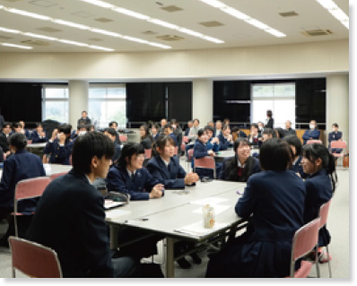 教室内でテーブルに座り語り合う学生たちの様子