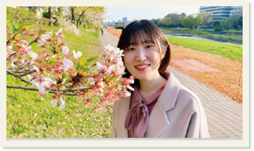 桜が咲く木のそばに立つ前原里咲さん