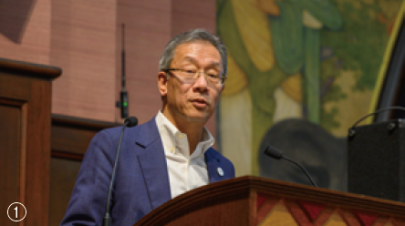 ①藤井総長が登壇している様子